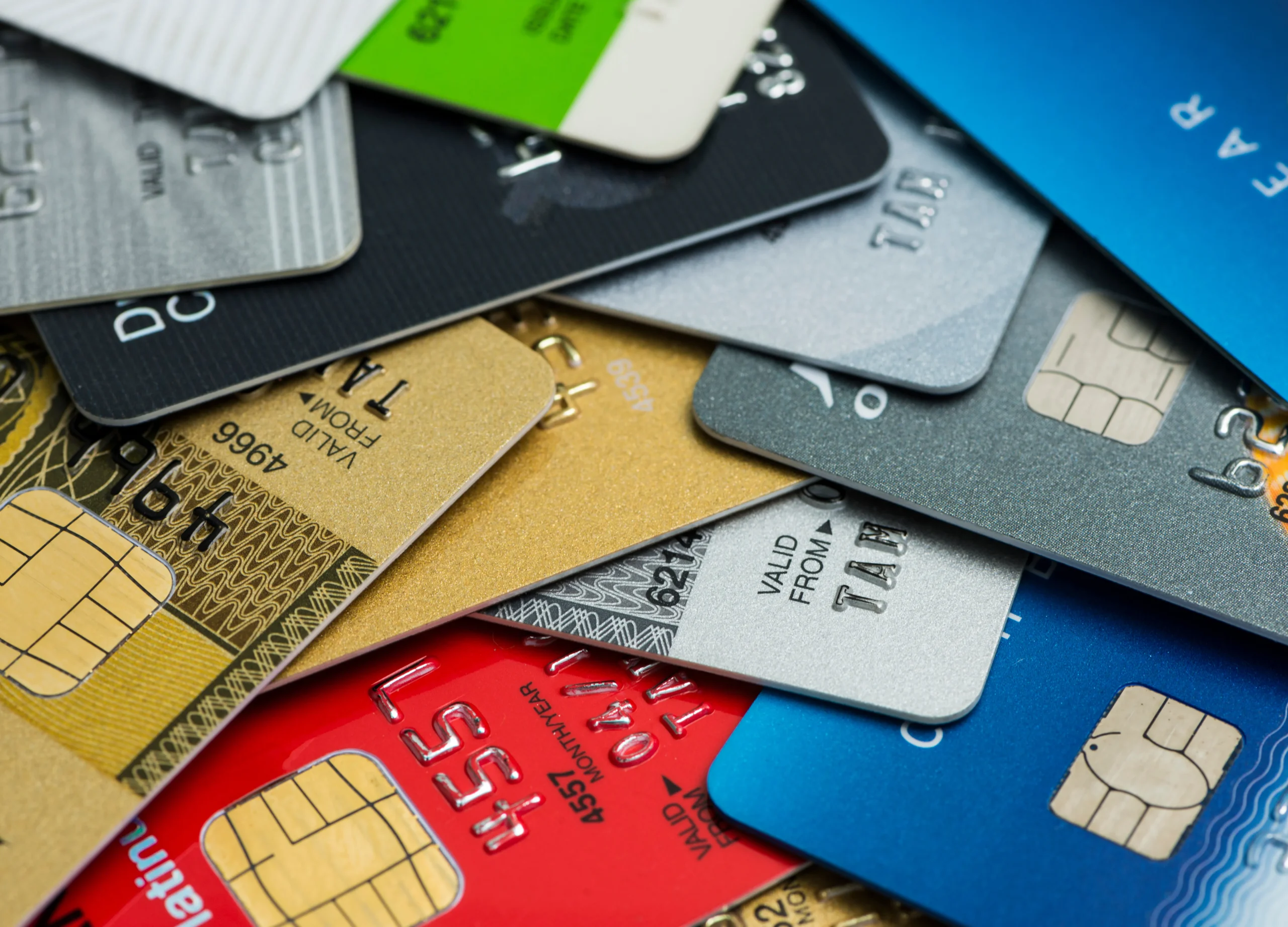 A close-up, overlapping stack of various multicolored credit and debit cards, representing the diverse options associated with a Credit Profile Number.
